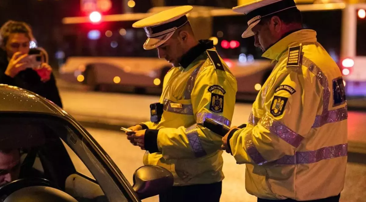 Agenții de la Poliția Rutieră verifică documentele unui șofer pe care l-au oprit în trafic