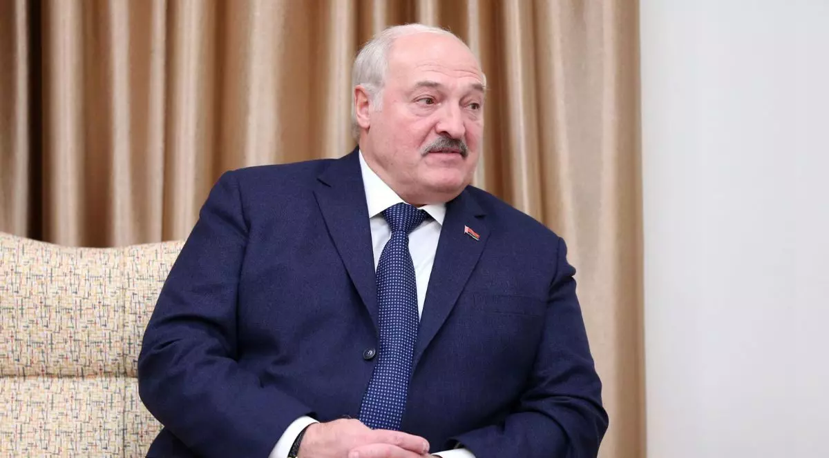 Aleksandr Lukașeko pe o canapea, îmbrăcat într-un costum bleumarin cu o cravată albastră și butoni batistp roșii