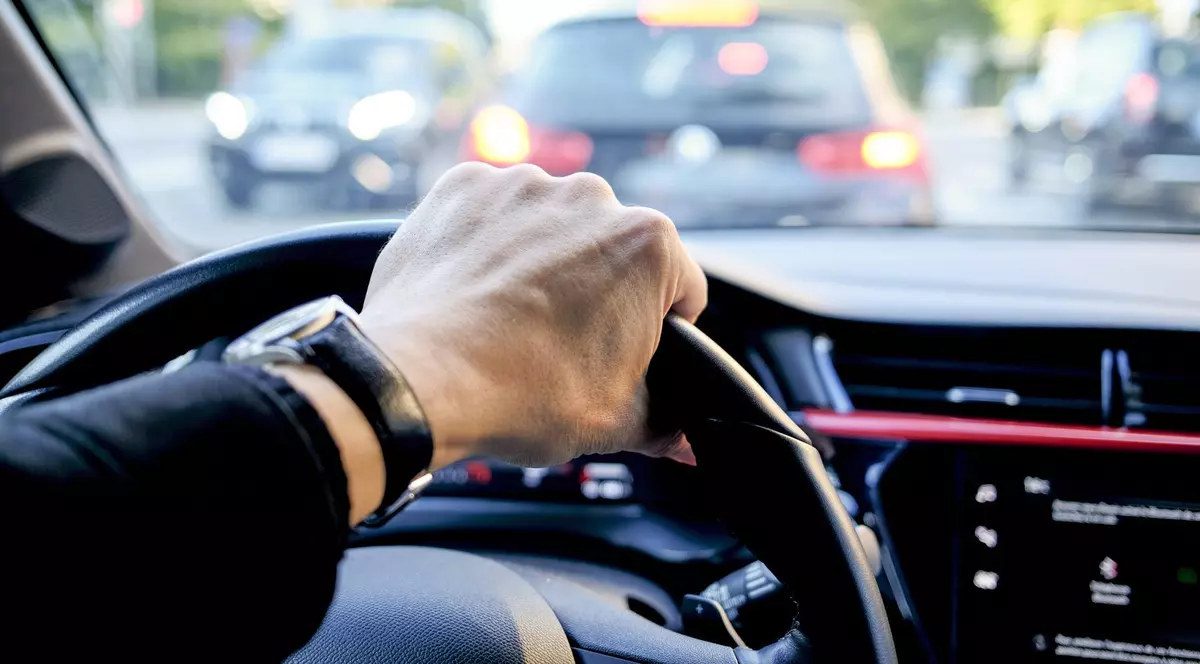 Bărbat care ține o mână pe volan.