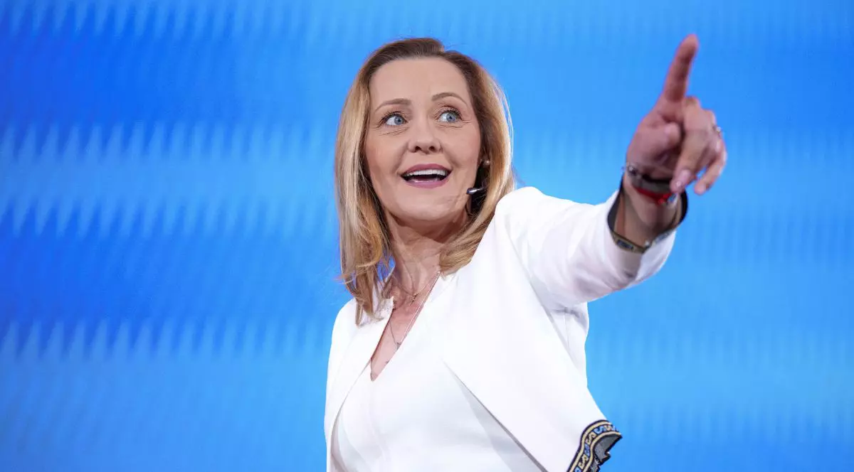 Elena Lasconi, într-un compeu alb, zâmbind, arătând cu degetul arătător spre dreapra