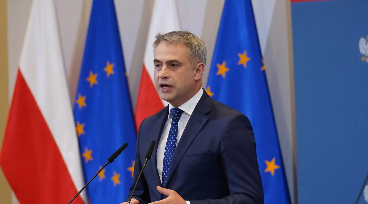 ministru Krzysztof Gawkowski polonia in timpul unui discurs, in spatele lui sunt steagurile poloniei si al ue