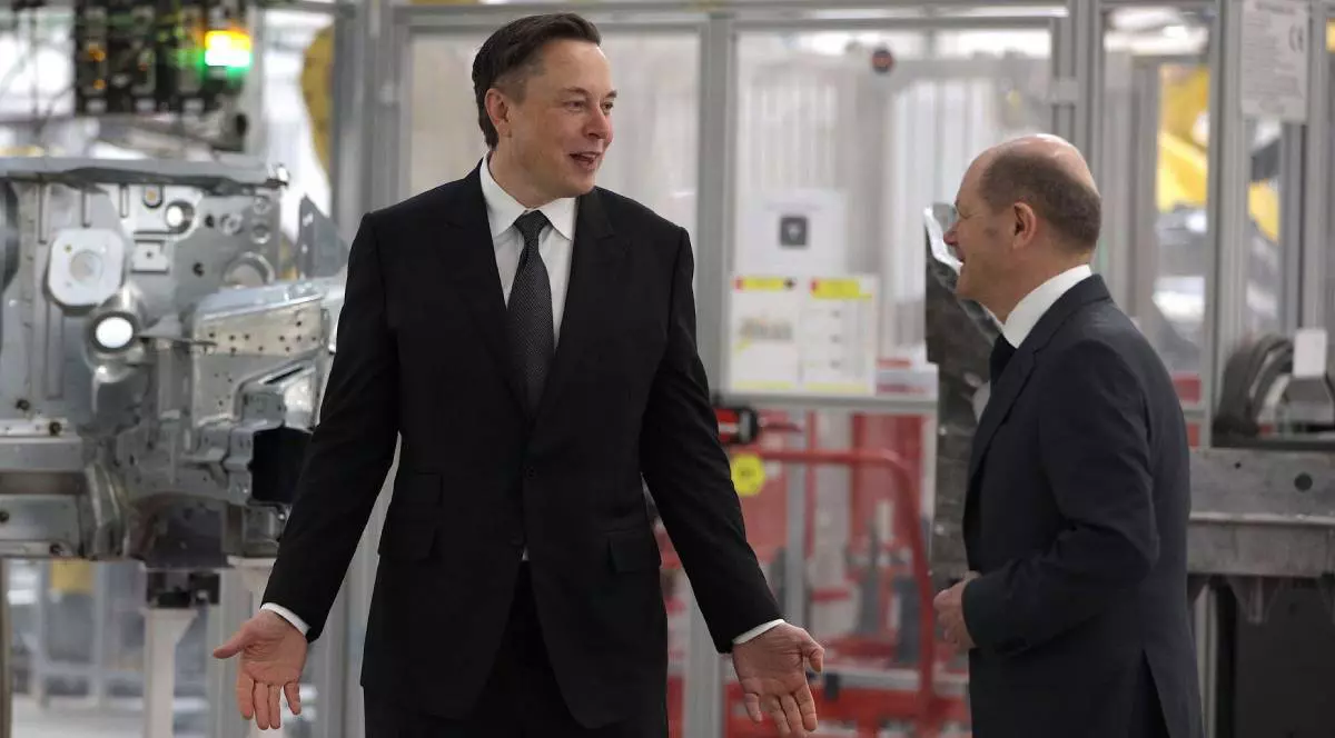 elon musk intr-o fabrica auto din germania gesticuland catre olaf scholz