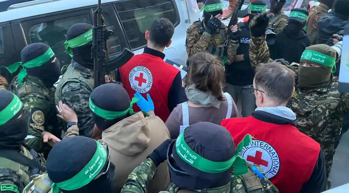 mai mulți palestinieni adunați lângă locul predării prizonierilor israelieni către reprezentanților Crucea Roșie, care poartă veste cu însemnele organizației