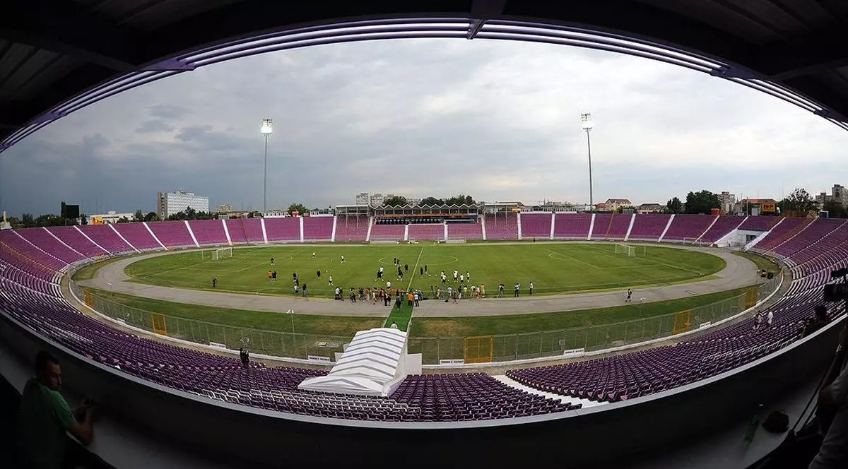 Vedere de pe stadionul Dan Păltinișanu din Timișoara, unde sunt mai mulți sportivi, iar scaunele din tribună sunt goale