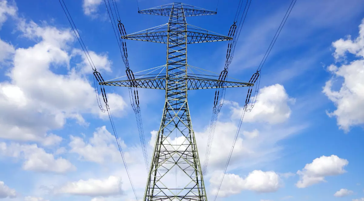 Austria este acuzată că nu lasă energia ieftină din Vest să ajungă în sud-estul Europei, inclusiv România, ceea ce face ca zona să aibă prețuri mai mari. Stâlp de înaltă tensiune pe fundal cu cer albastru și nori albi