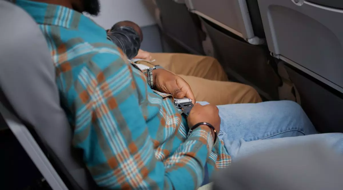 bărbat care își pune centura de siguranța în avion