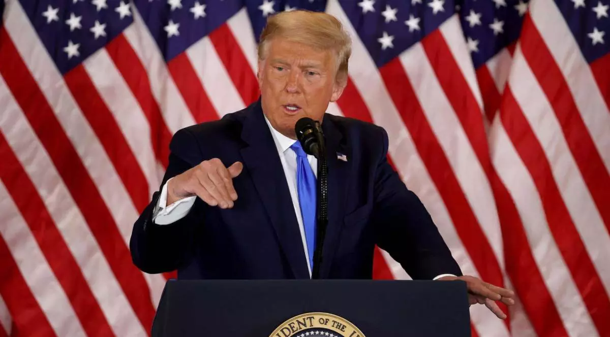 donald trump in timpul unui discurs, in spatele sau steagul americii