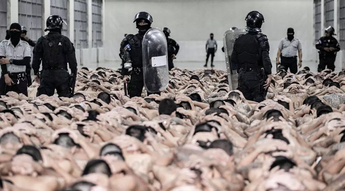 Mai mulți deținuți, cu mâinile ridicate, păziți de polițiști, într-o închisoare din El Salvador - iunie 2024