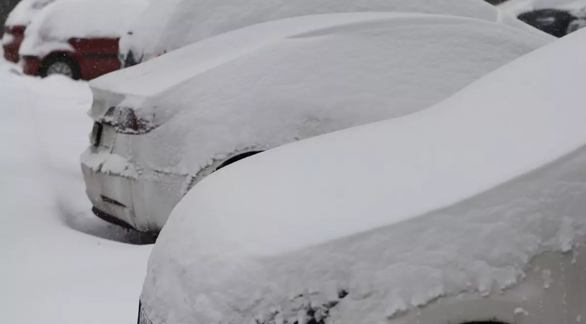 Mai multe mașini acoperite de zăpadă stau în parcare, pe o stradă din București, iar pe jos este un strat gros de omăt
