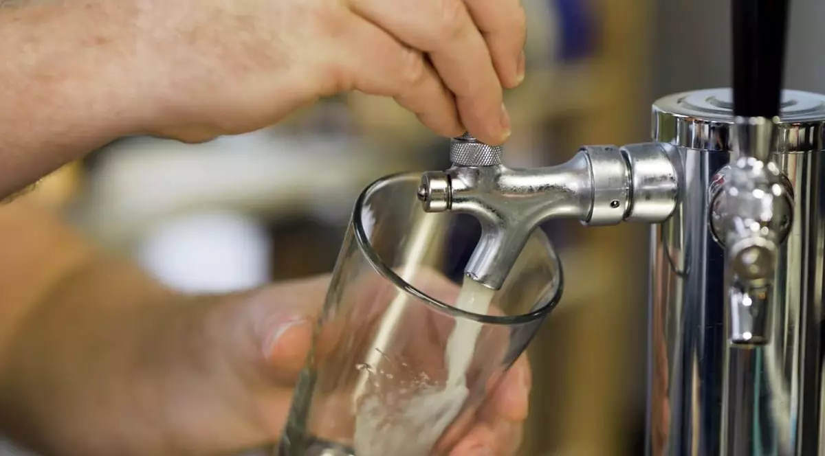 Un barman umple cu grijă o halbă de bere