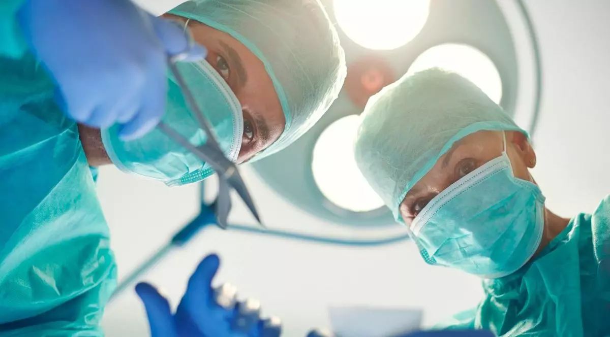 Doi medici chirugi pregătiți de o intervenție. Ambii sunt echipați corespunzător