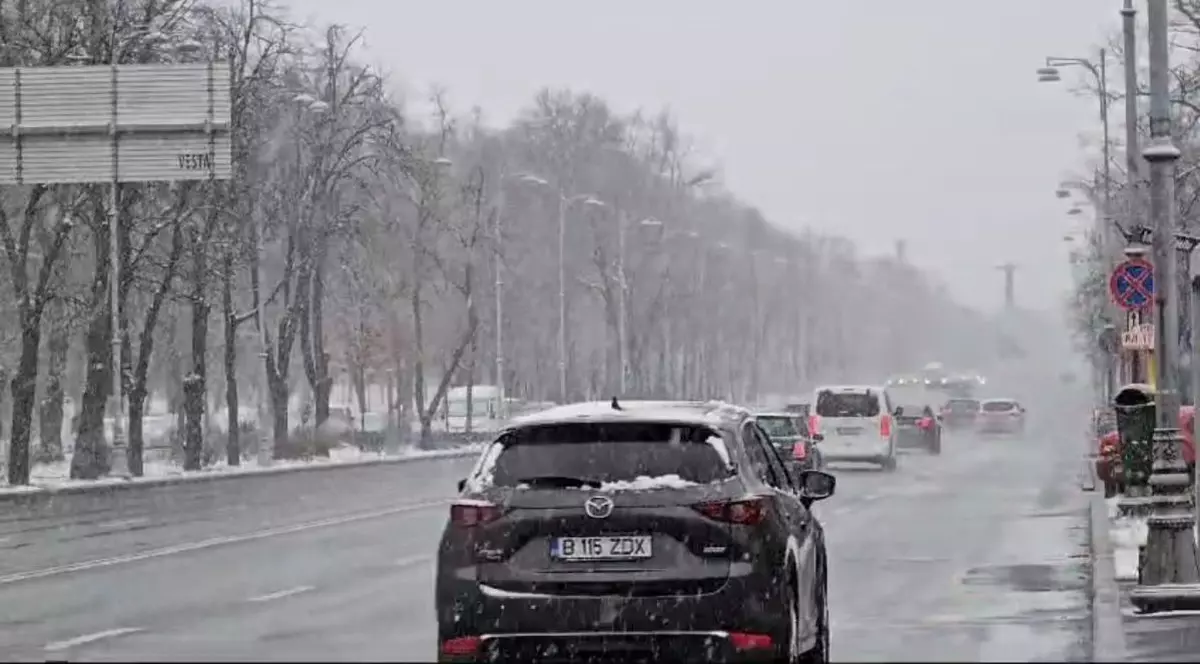 Mai multe mașini circulă pe Bulevardul Aviatorilor din București, pe timp de iarnă, iar pe străzi se vede ninsoare