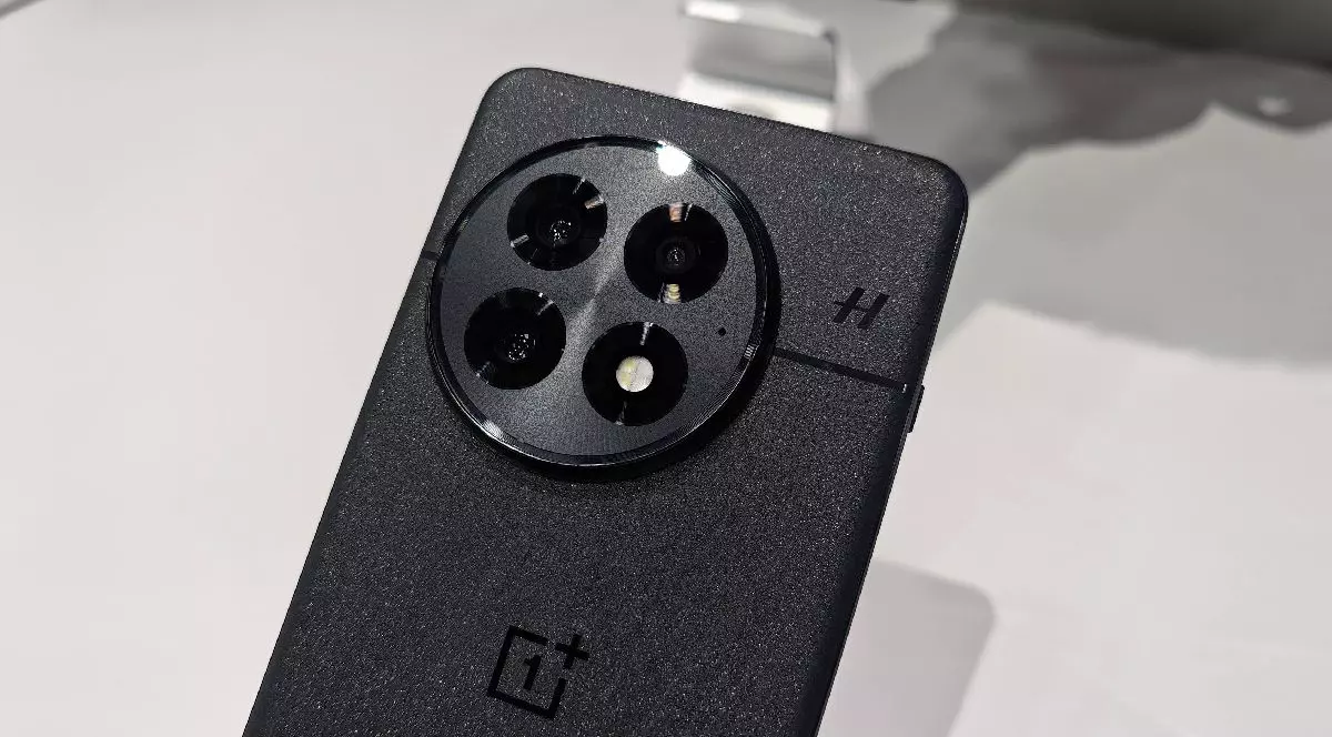 Un telefon OnePlus 13 gri, cu spatele spre privitor, pe un fundal alb.