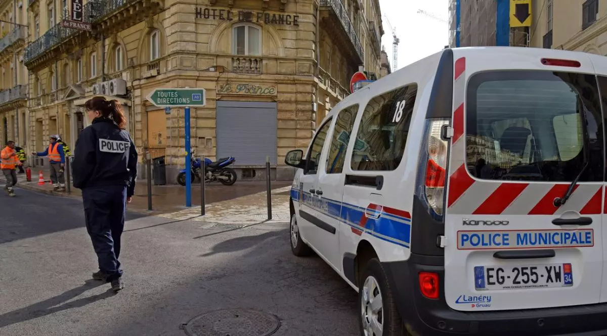 Prim plan mașină de poliție din Franța în plină stradă, alaturi o femeie polițist care a închis o stradă pentru un incident în Montpellier, Franța