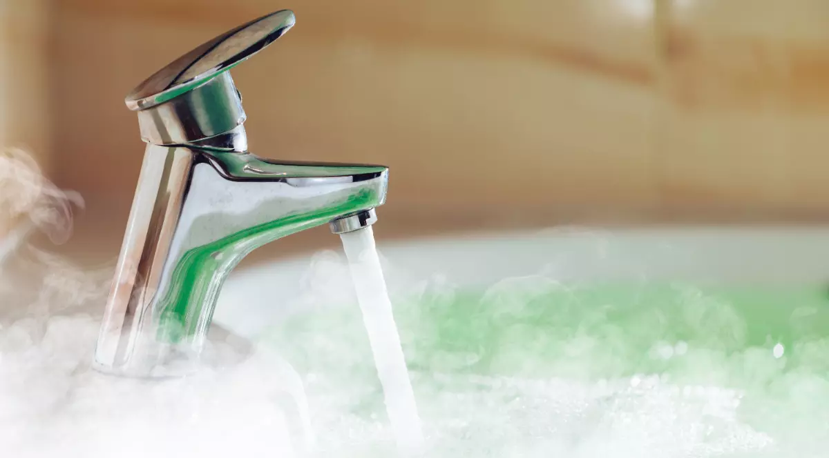 Un robinet este deschis și curge apă fierbinte într-o cadă