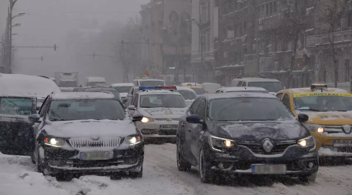 multe masini in trafic bara la bara, drumul este acoperit cu zapada, printre masini se afla o autospeciala de politie