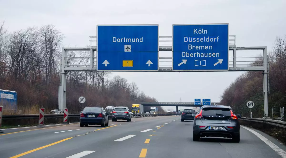 mai multe masini pe o autostrada din germania. sunt pancarte pe care arata directia de mers pentru diferite orase din germania