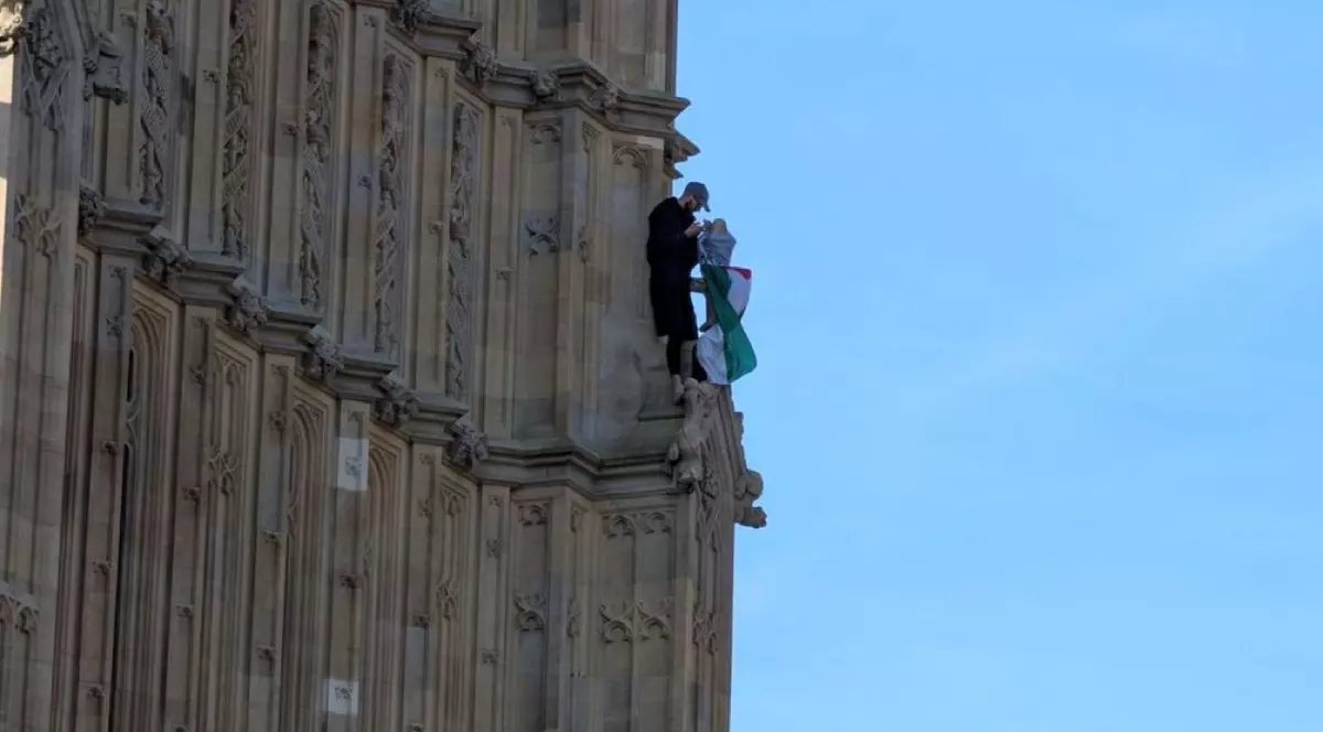 Bărbat urcat pe Palatul Westminster cu un steag palestinian.