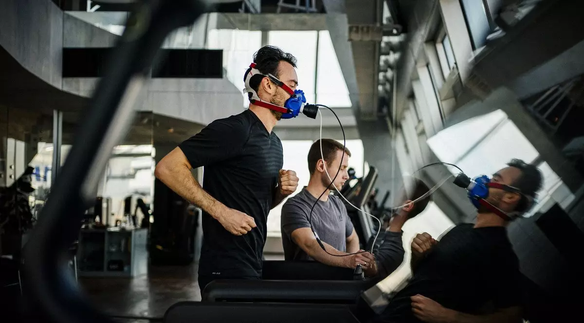 Un bărbat face exerciții pe o bandă de alergare purtând o mască facială pentru a analiza gazele din respirația sa la o sală de sport care se autointitulează „laborator de biohacking”