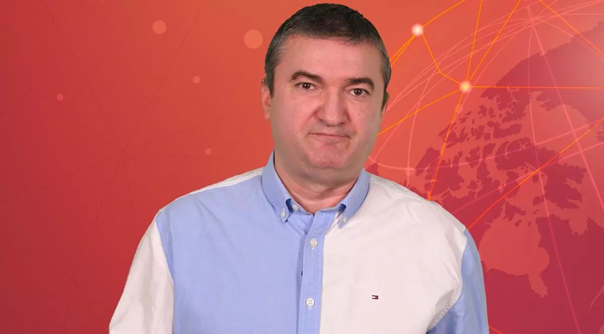 Dorin Chioțea, redactor-șef Libertatea, îmbrăcat cu o cămașă de culoare alb-bleu, pe fundal roșu, în studioul 5 știri by Libertatea