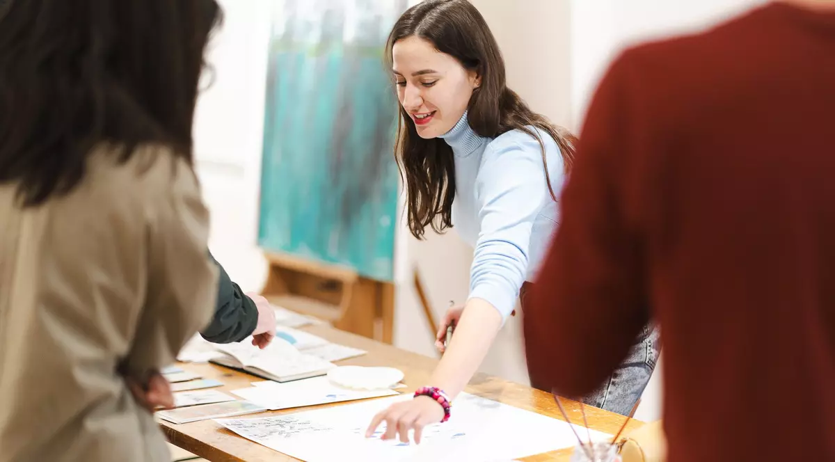 Imagine cu o femeie care aranjează lucrări pe o masă.