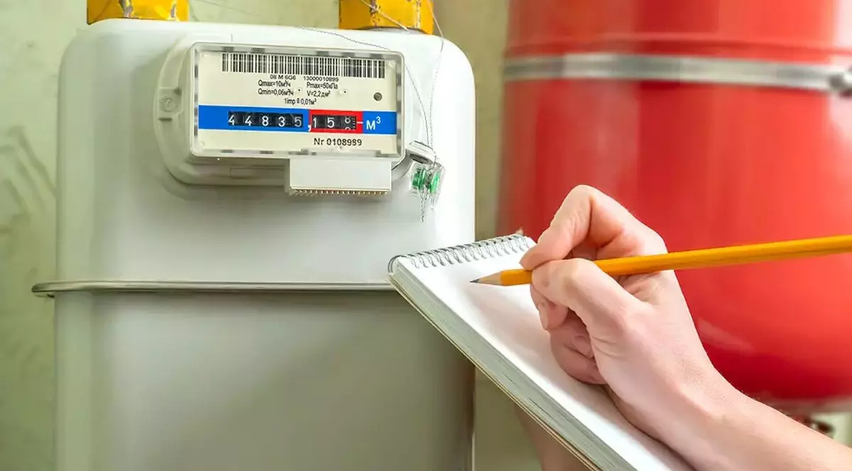 O femeie scrie pe caiet indexul de la contorul de lumină