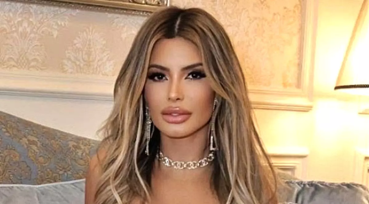 Janaina Prazeres, în prim-plan, cu un colier la gât și pe fundal o lampă