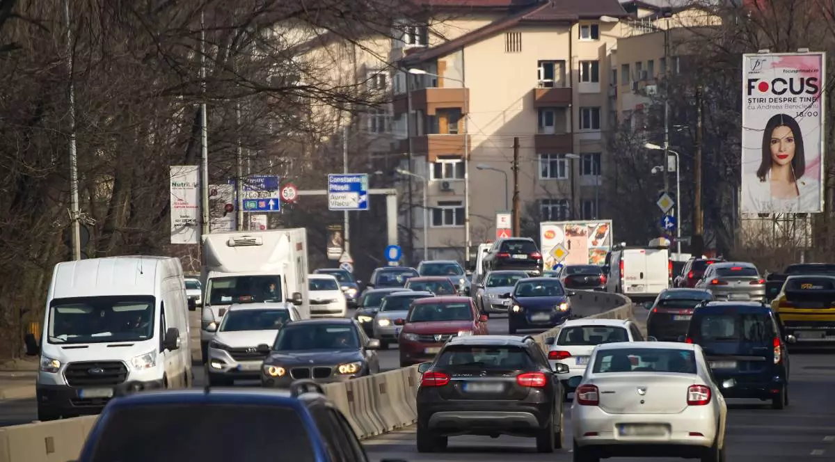 mai multe masini aflate in trafic pe un drum cu trei benzi pe sens. se observa masinile din ambele sensuri si cateva indicatoare rutiere