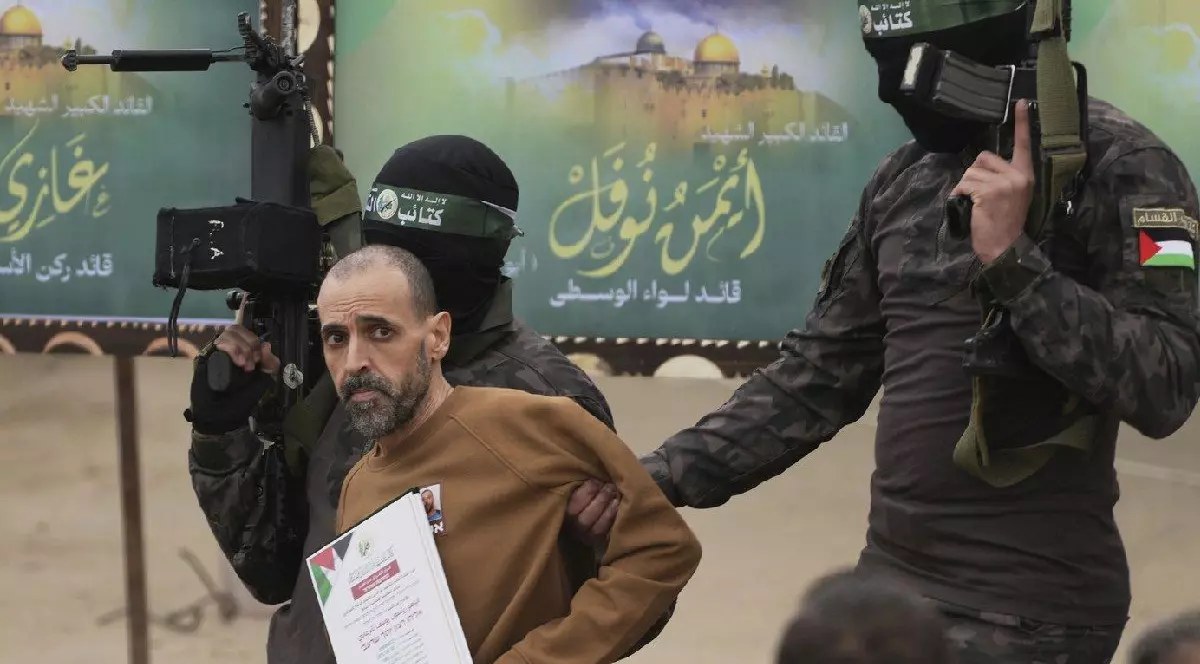 Prizonierul israelian Eli Sharabi, ținut ostatic de Hamas în Gaza din 7 octombrie 2023, este escortat de luptători Hamas înainte de a fi predat Crucii Roșii în Deir al-Balah, centrul Fâșiei Gaza, 8 februarie 2025.