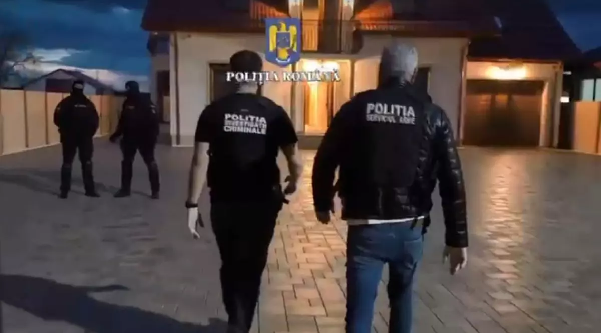 Polițiști și mascați în timpul unor descinderi în curtea unei case, noaptea