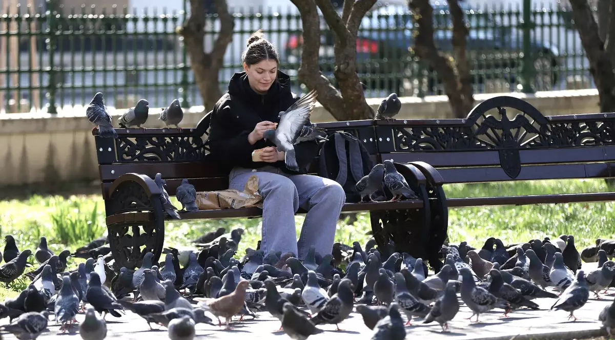 Tânără surprinsă în timp ce dă mâncare unor porumbei