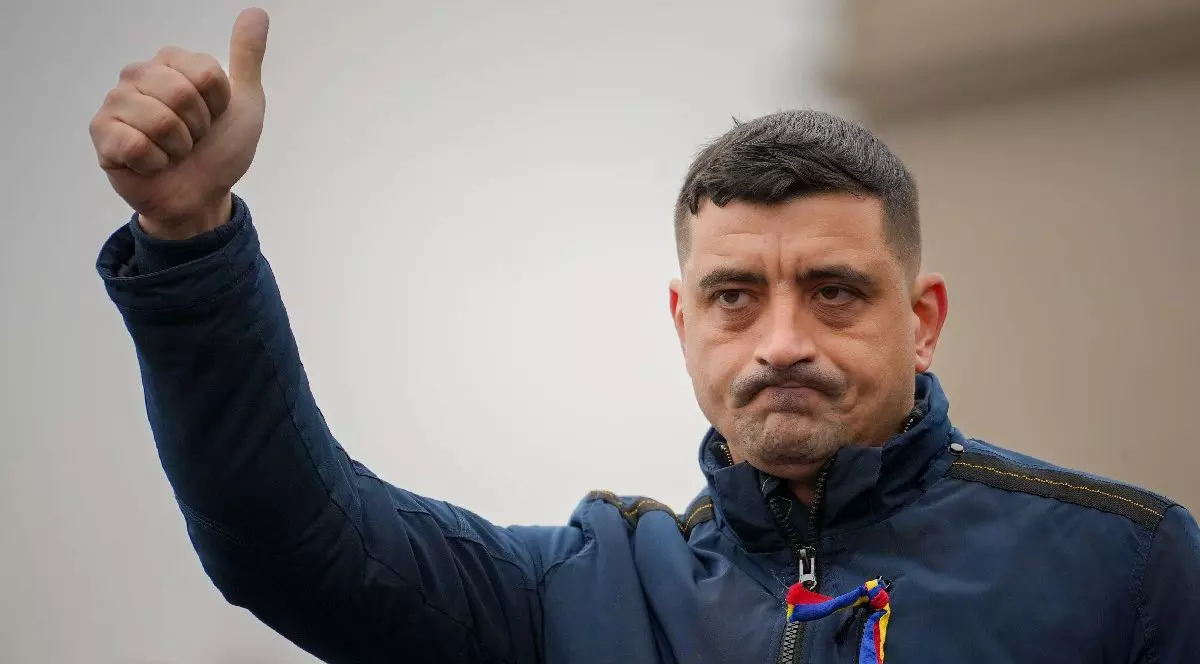 George Simion, liderul AUR, îmbrăcat în geacă albastră, cu un tricolor în piept, cu mâna dreaptă ridicată