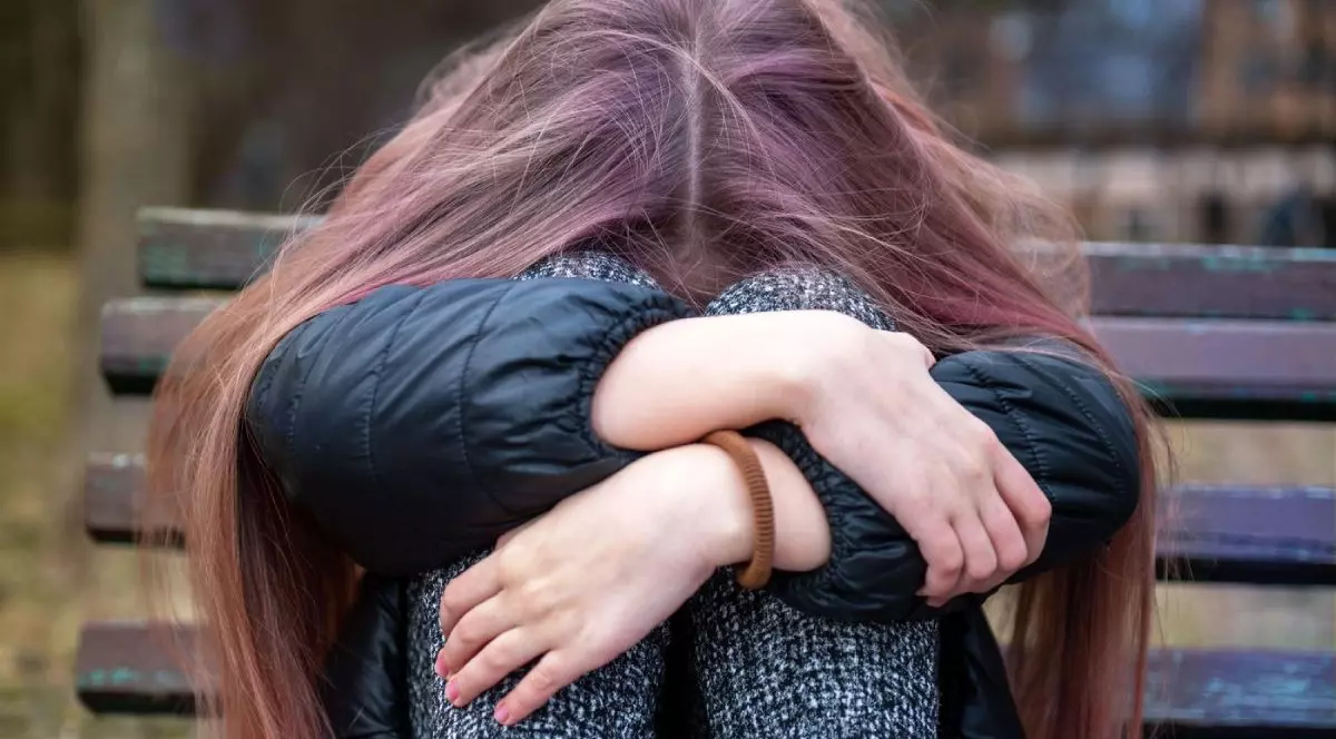 Tânără deprimată tristă stând pe o bancă într-un parc