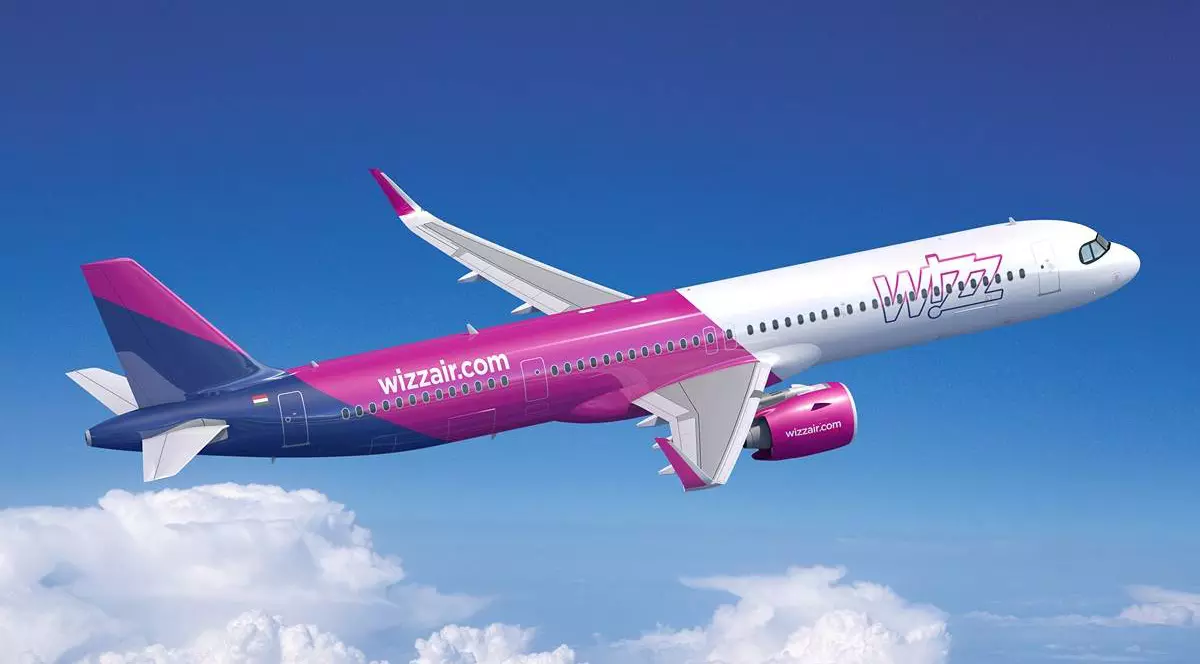 avion care apartine companiei wizz air, modelul Airbus A321neo. fuselajul este vopsit în culorile specifice companiei: roz, violet și alb.