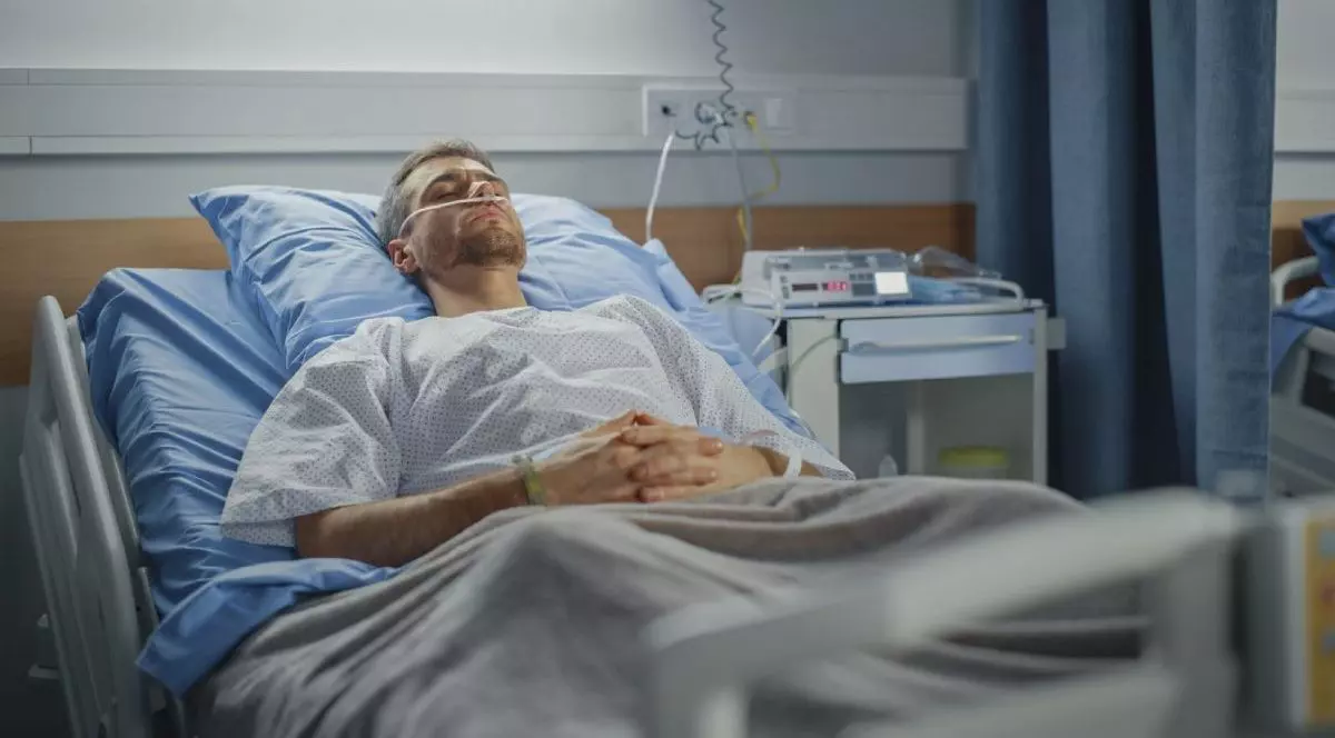 Imagine creativă cu un bărbat aflat întins într-un pat de spital, acoperit cu o pătură