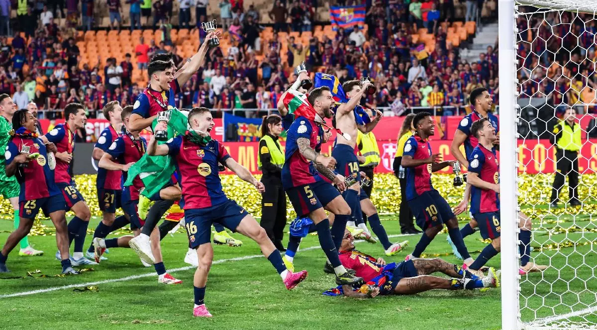 Mai mulți jucători de fotbal de la FC Barcelona se bucură în fața unei porți, pe un stadion