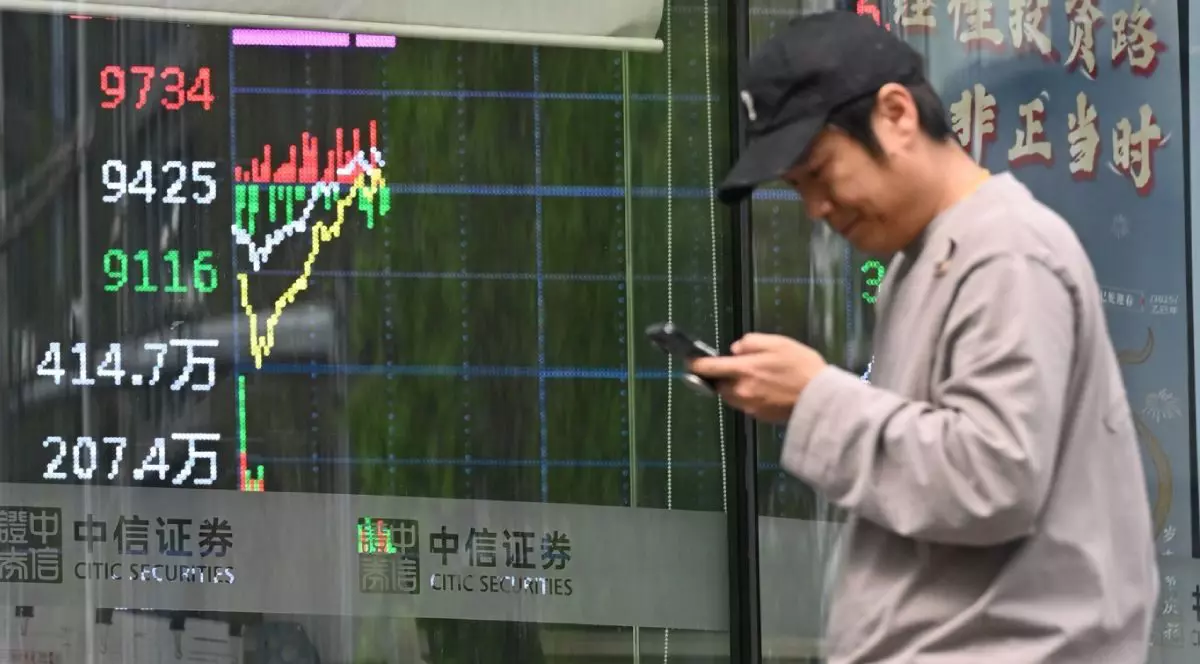 Un bărbat într=o geacă crem trece pe lângă un ecran care arată tranzacționarea acțiunilor la Beijing pe 9 aprilie 2025.