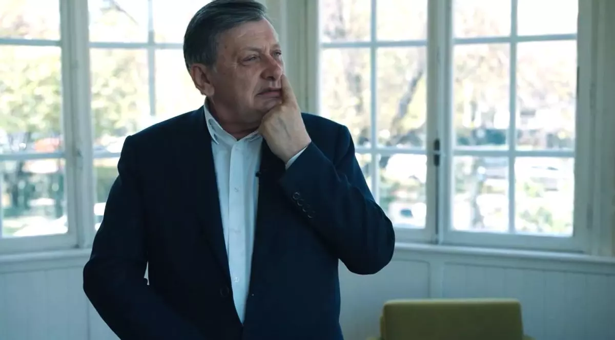 Crin Antonescu, îmbrăcat în costum și cămașă albă, fără cravată, în fața unei ferestre albe, în timp ce își ține degetul pe nas și se gândește