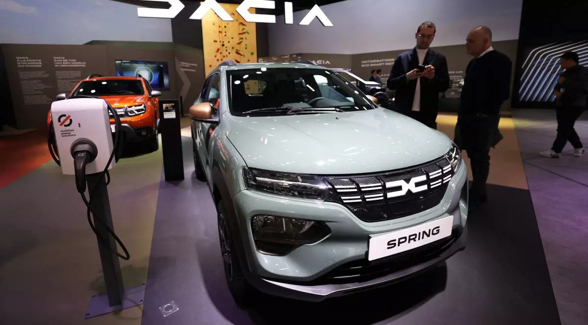 masina electrica dacia spring expusa intr-un showroom. in jurul masinii sunt cateva persoane care studiaza automobilul