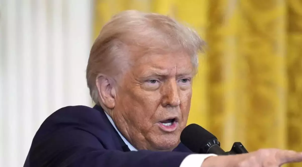 În imagine este ilustrat Donald Trump, îmbrăcat în costum negru și cămașă albă. Acesta vorbește la microfon