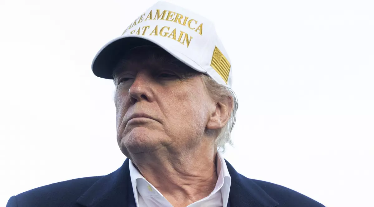Donald Trump cu o șapcă albă pe cap, pe care scrie cu litere aurii „Make America Great Again”