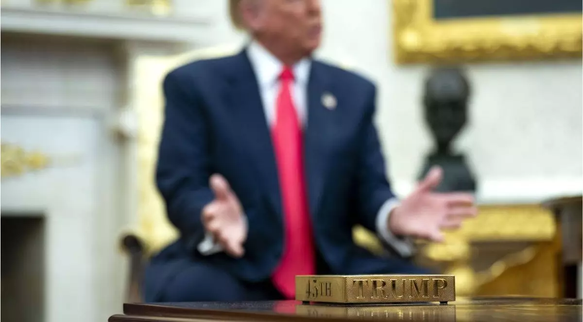 Fotografie în ceață cu Donald Trump. În prim-plan, un suport de cană din aur.