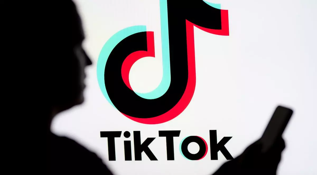 O femeie se uitâ pe un smartphone cu o siglă TikTok afișată în fundal