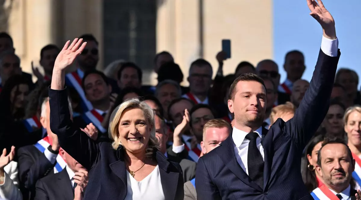 Jordan Bardella și Marine le Pen, ridicând mâna în aer, îmbrăcați în costume negre cu cămăși albe