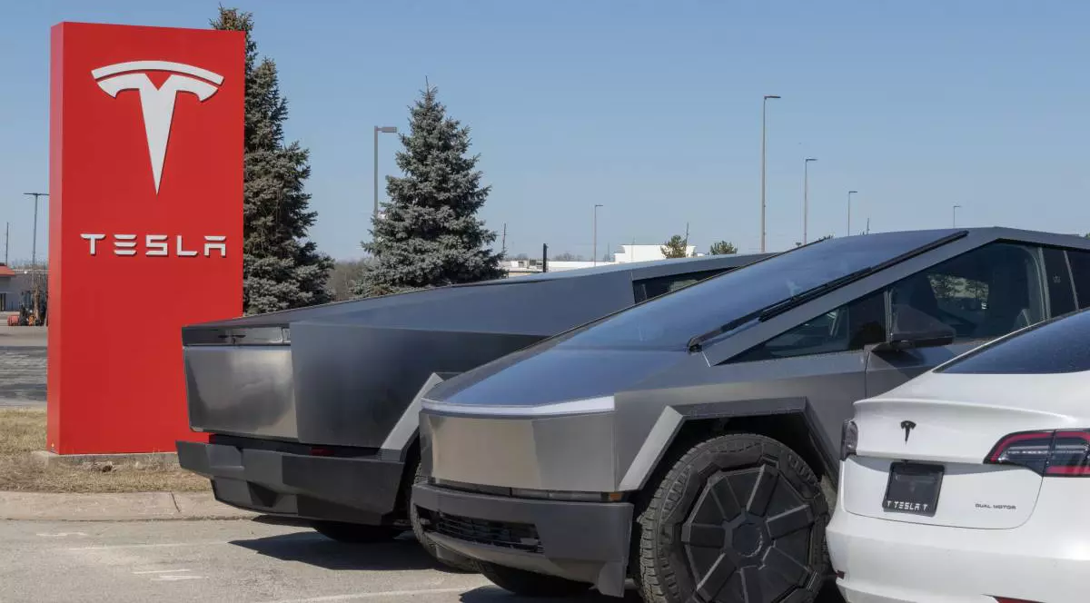 parcarea unui showroom sau sediu Tesla, unde sunt expuse mai multe modele electrice. În prim-plan sunt două exemplare ale Tesla Cybertruck, alături, apare un model Tesla Model Y alb