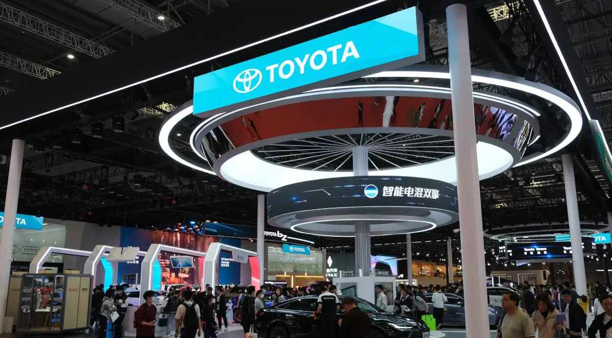 Stand al companiei Toyota la un târg internațional auto din China cu ecrane LED care afișează logo-ul Toyota și mesaje în limba chineză. În mijlocul standului se află o mașină neagră de prezentare