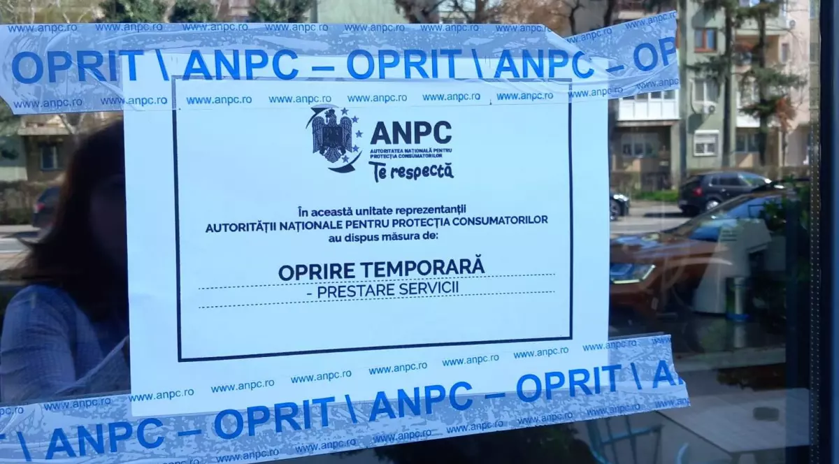 O foaie lipită cu o bandă albă, pe care scrie „ANPC”, de geamul unui magazin închis