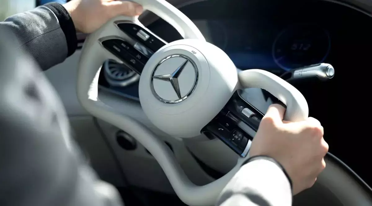 Interiorul unei mașini Mercedes Benz, în prim plan este noul design al volanului, asemanator cu manșa unui avion. se observă sigla mercedes de culoare argitie, iar volanul este de culoare alba dintr-un material de piele