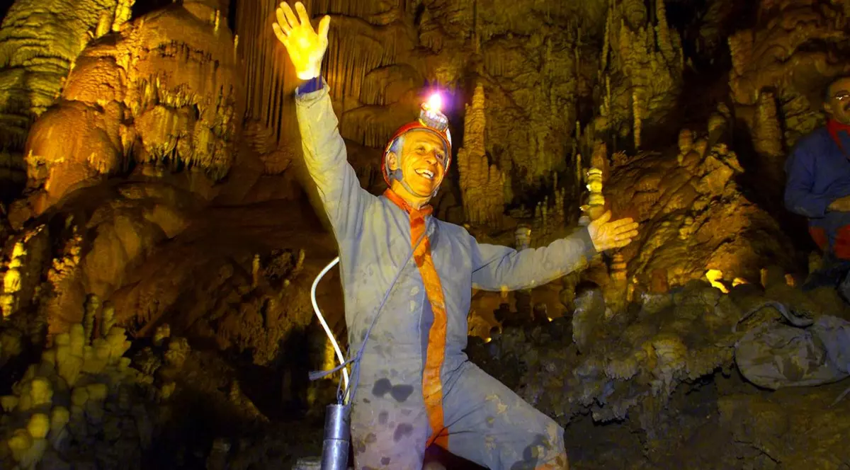 În imagine este ilustrat un bărbat îmbrăcat în costum albastru și se află într-o peșteră