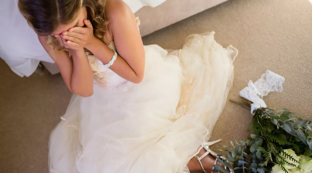 o mireasă care plânge cu un buchet de flori lângă ea